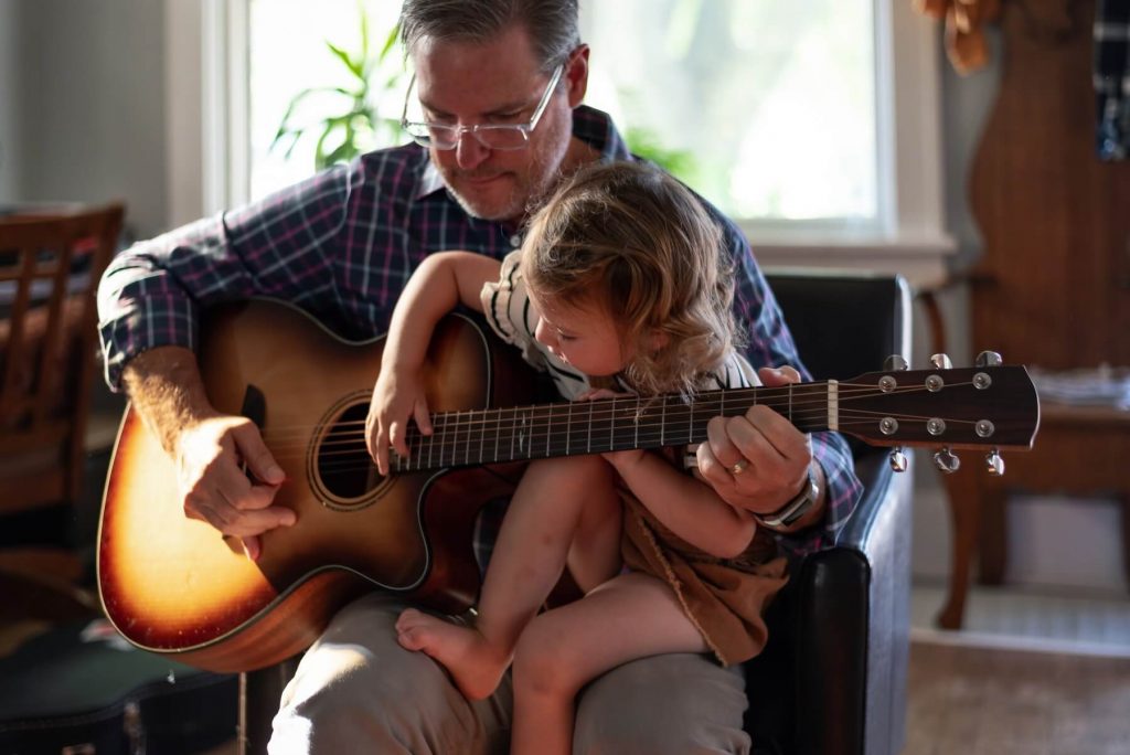 adult teaching a child how to play guitar