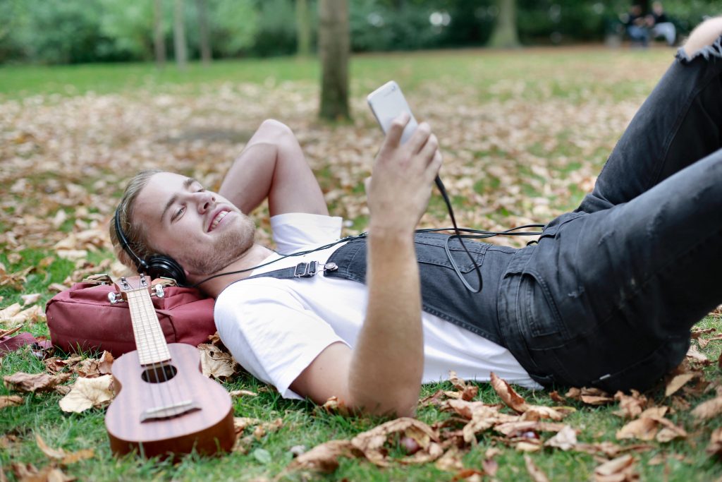 man listening to relaxing music while lying down in a park