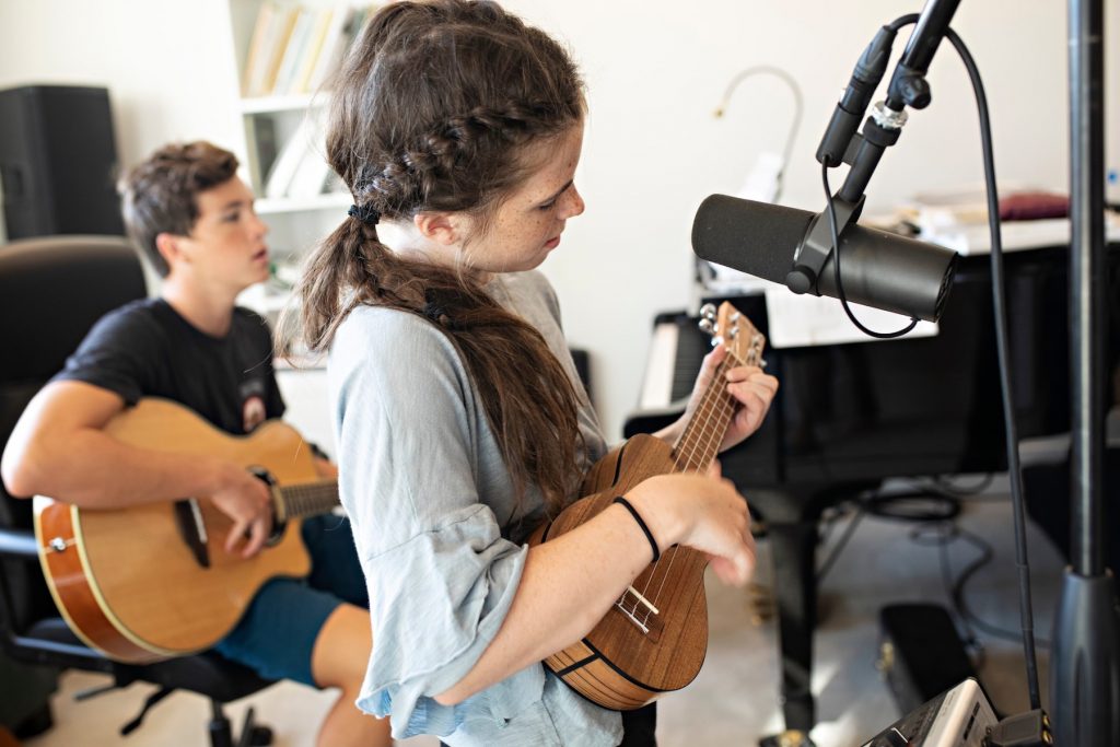 girl playing ukulele and boy playing guitar