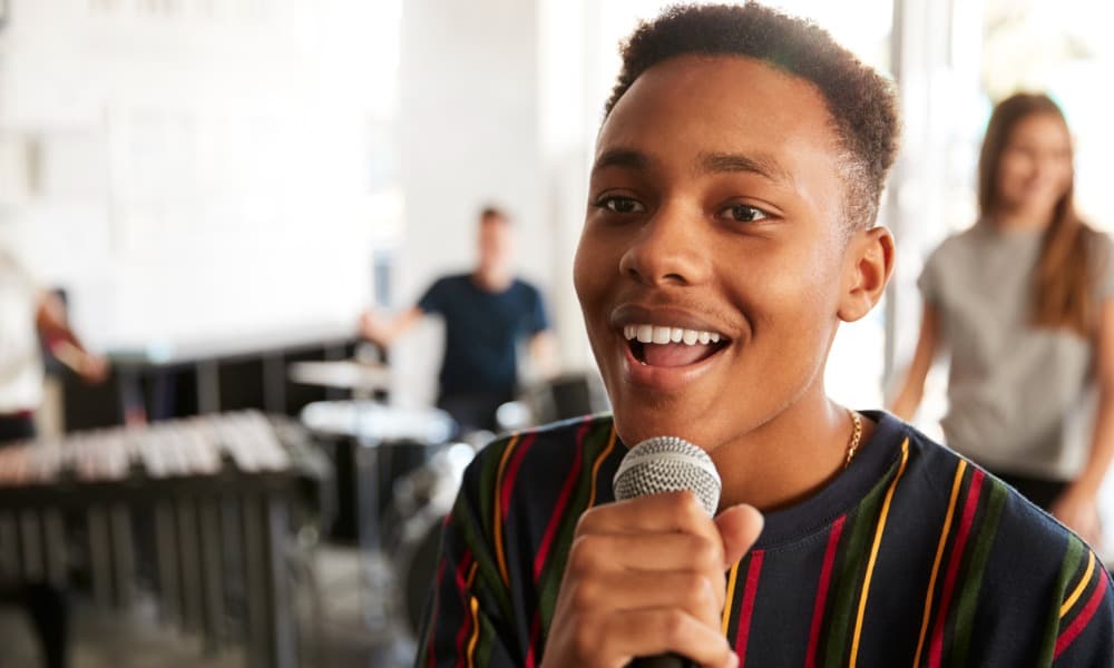 A young man enjoying voice lessons by singing into a microphone