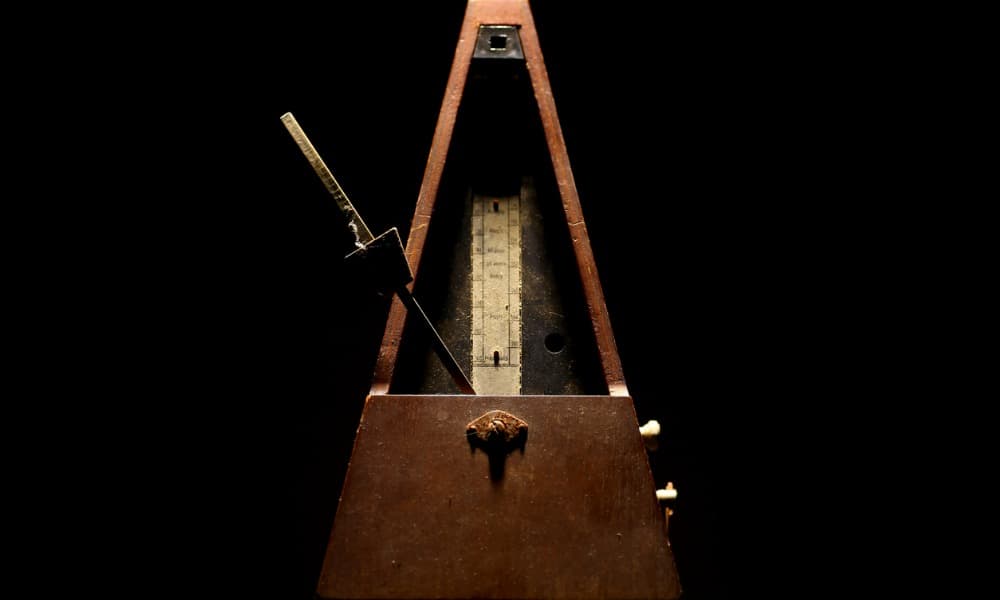 A wooden metronome used to improve rhythm sits on a black background.